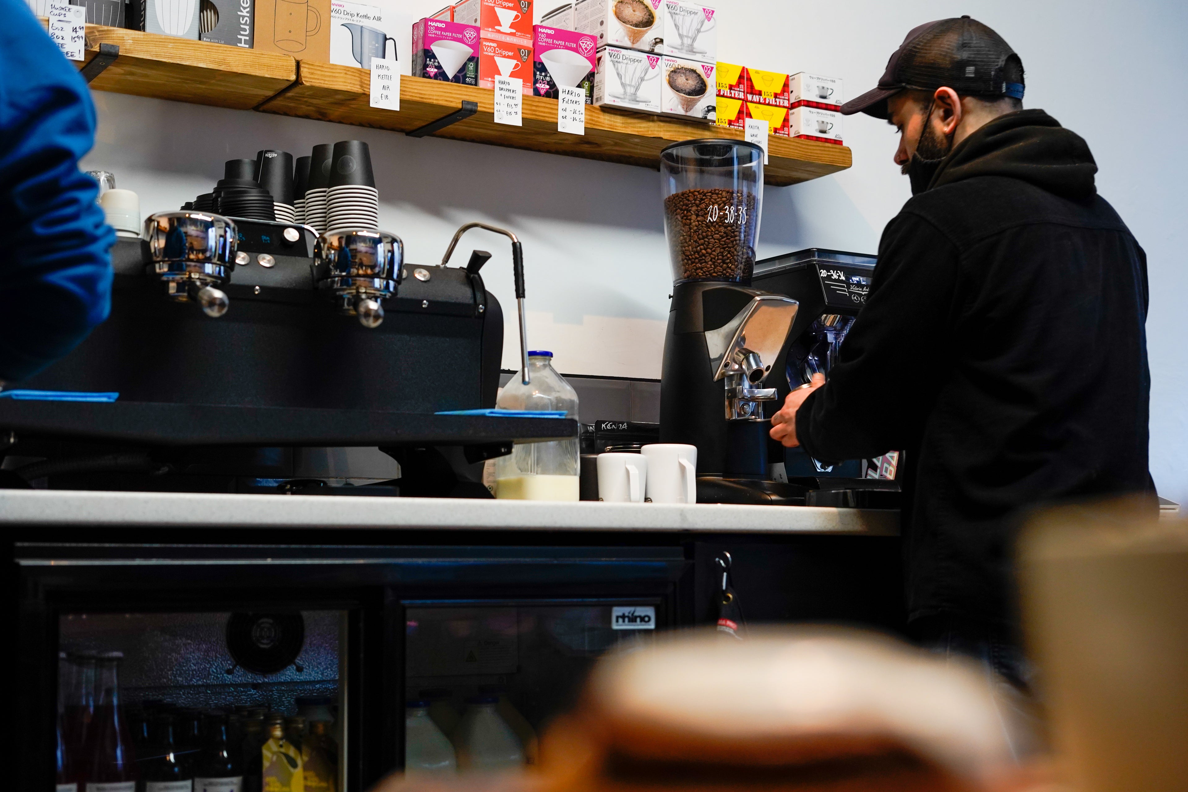 Barista operating a coffee machine in a coffee shop.